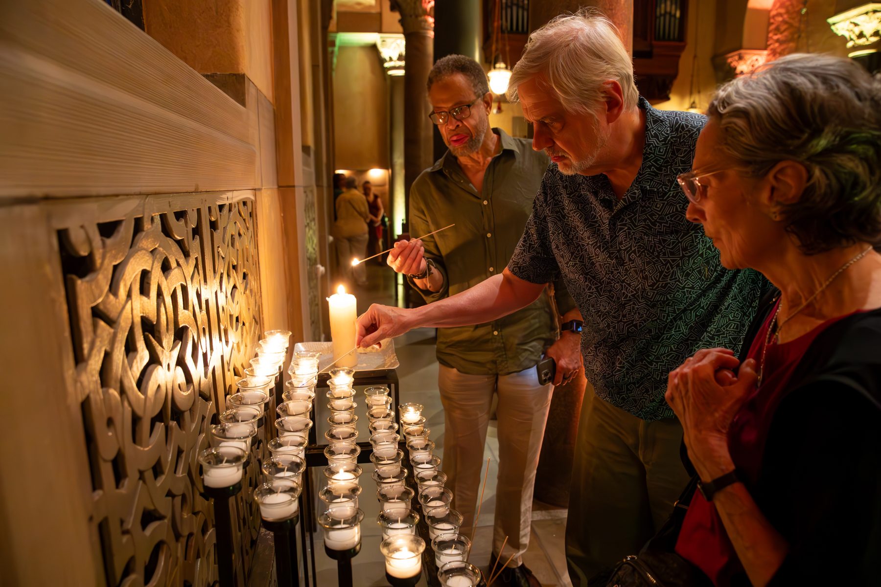 People lighting votive candles during the service