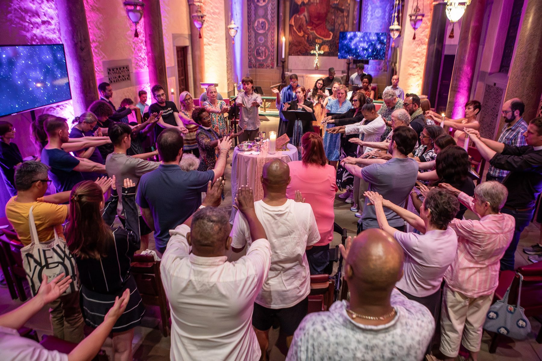 Worshippers gathered in the round with hands raised
